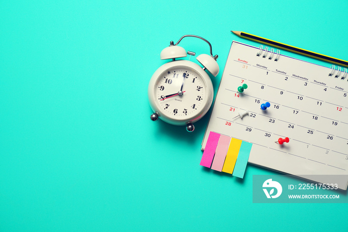 close up of calendar and alarm clock on the green table, planning for business meeting or travel planning concept