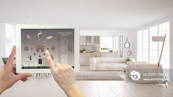 Smart remote home control system on a digital tablet. Device with app icons. Modern scandinavian living room with sofa and kitchen in the background, architecture interior design