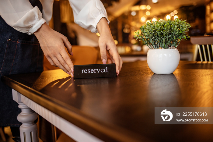 Restaurant Chilling Out Classy Lifestyle Reserved Concept. Waitress reserving a tablet at a restaurant and putting a sign on the table - food service concepts