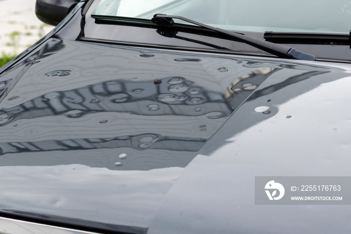 Bumped car engine hood after heavy storm as extreme weather and fallen trees and hail damage shows car insurance needs for auto repair and weather insurance for victims and emergency coverage danger