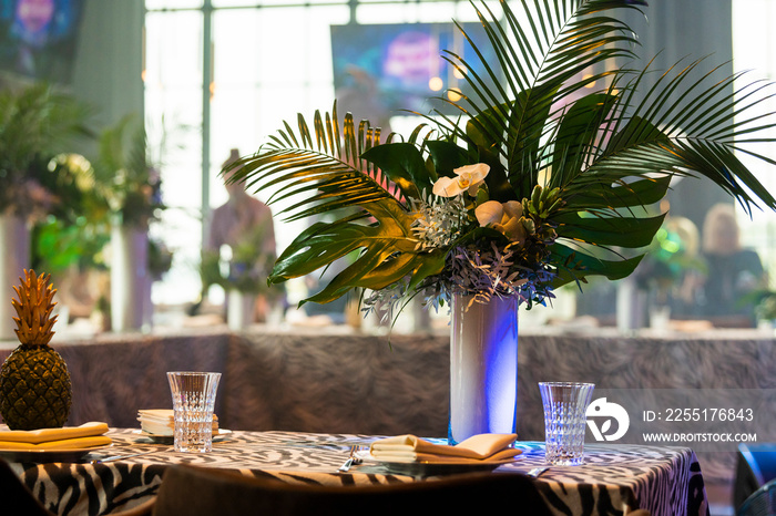 decoration of green leaves on a banquet table, floristry of tropical monstera leaves and palm branches of orchids