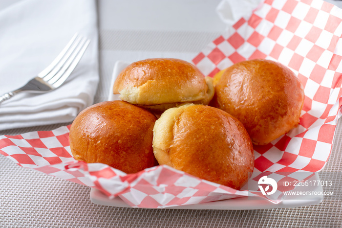 A view of a plate of baked brioche rolls, in a restaurant or kitchen setting.