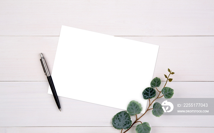 Blank paper sheet copy space with mockup and leaf on wooden table, poster and invitation, postcard decoration your design or branding, simplicity and minimal, nobody, flat lay, top view.