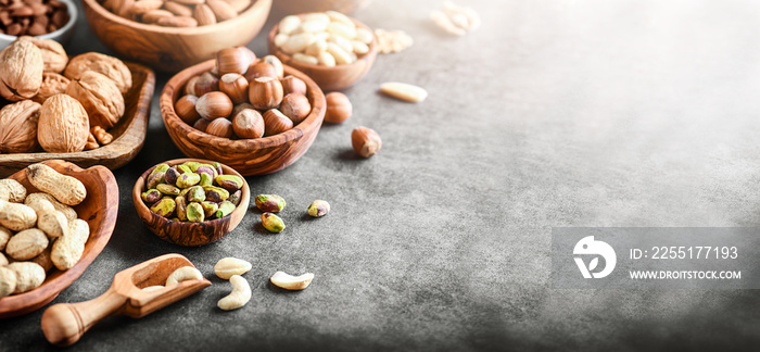 A variety of nuts in wooden bowls from top view copy space. Walnuts, cashew, almond, pistachio, pecan, hazelnut, macadamia and peanut mix selection. Healthy fitness super food banner or panorama.