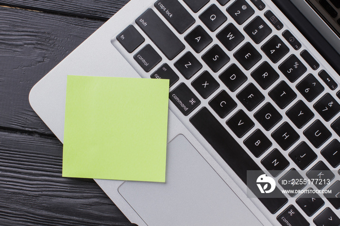 Close up laptop keyboard with blank sticker for copy space. Top view flat lay. Dark wooden background.