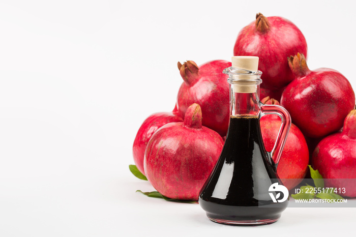 Grenadine in bottle and pomegranates on white background