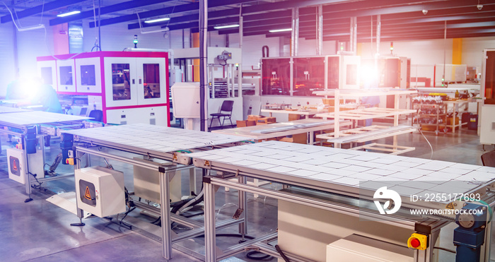 workers and machinery in a solar panel manufacturing industry factory.