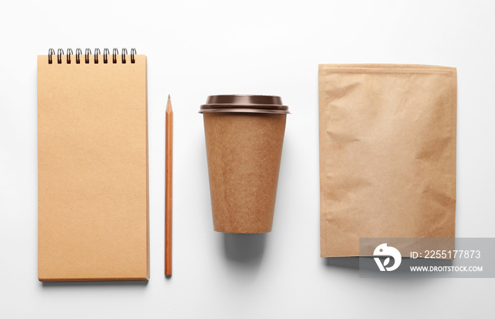 Composition with blank cup, paper package and notebook as mockups for branding on white background