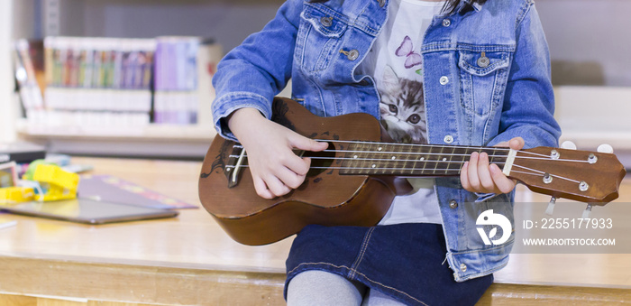 Little child playing ukulele in the library bossanova music in summer time, Cute girl play guitar vintage style, hand picking Guitar ,Ukulele on the library .