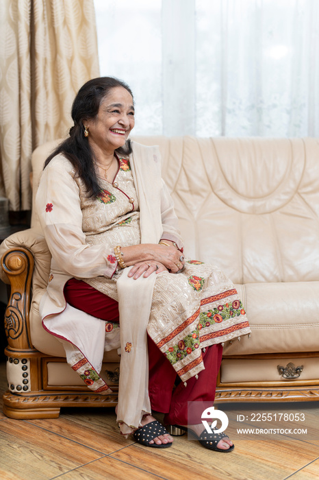 Cheerful senior woman sitting on sofa in living room