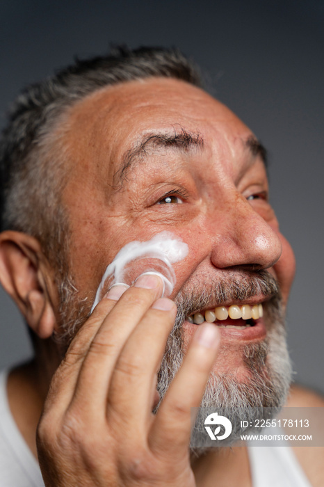 Portrait of smiling man applying face cream