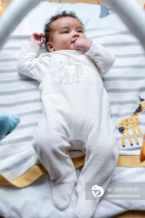 Baby girl lying on play mat at home