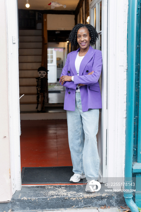 Smiling woman in purple jacket standing by front door