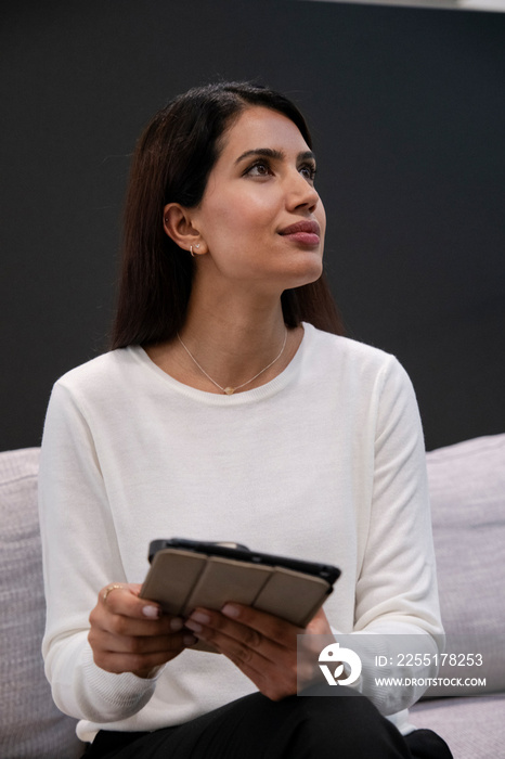 Woman sitting on sofa and using digital tablet