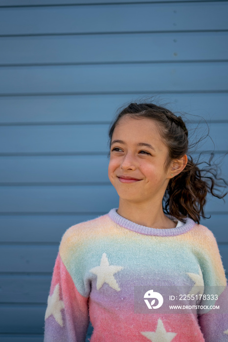 Smiling girl (8-9) in colorful clothes standing outdoors