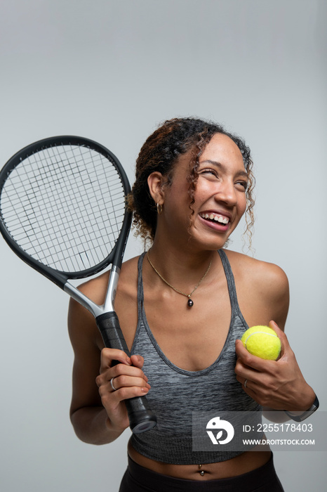 Smiling woman holding tennis racket and ball