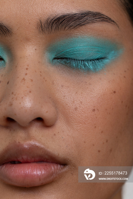 Woman with closed eyes wearing blue makeup