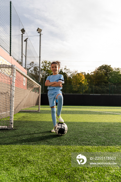 Portrait of girl (6-7) with ball next to soccer goal