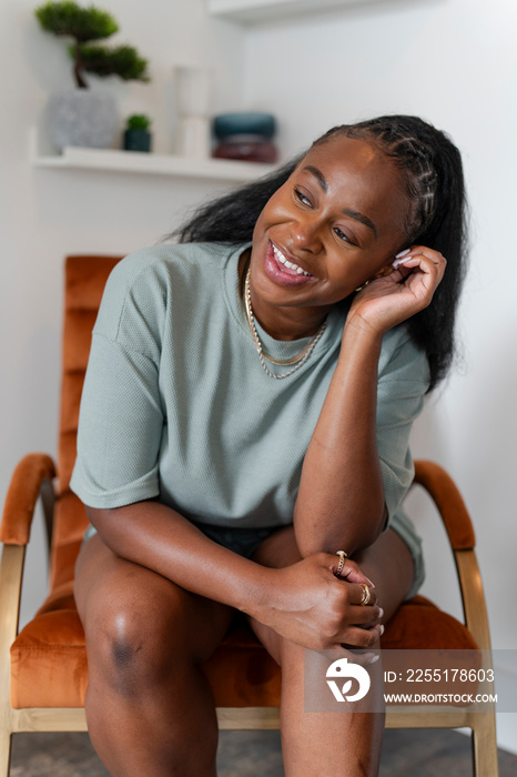 Portrait of young woman sitting in armchair at home