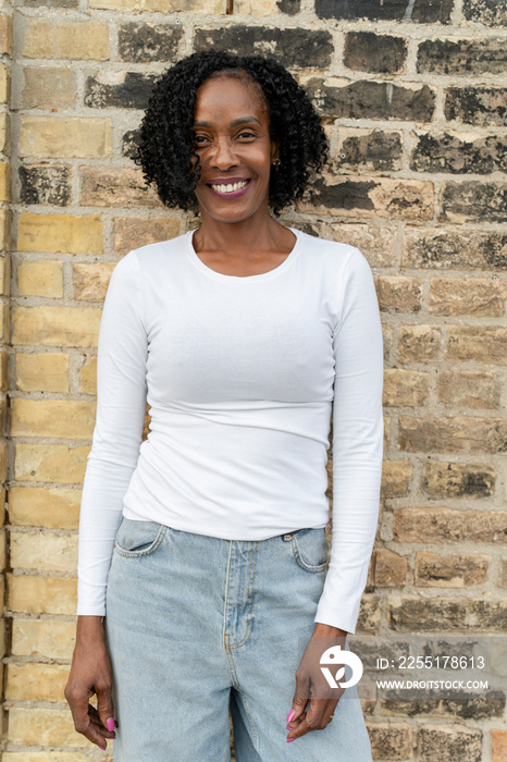 Portrait of smiling woman standing by brick wall