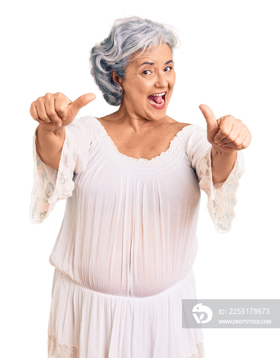 Senior woman with gray hair wearing bohemian style approving doing positive gesture with hand, thumbs up smiling and happy for success. winner gesture.