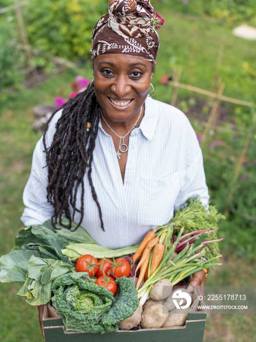 Portrait of smiling mature woman holding vegetables from garden