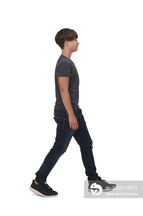 side view  of a teen with jeans and sneakers walking on white background