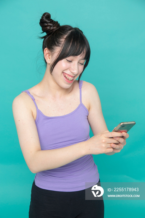 Studio shot of smiling girl looking at smart phone