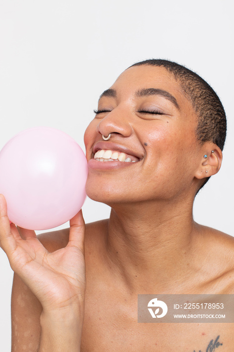 Studio portrait of smiling woman holding pink balloon