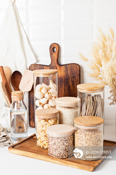 Assortment of cereals and pasta in glass jars and woden kitchen utensils. Zero waste idea