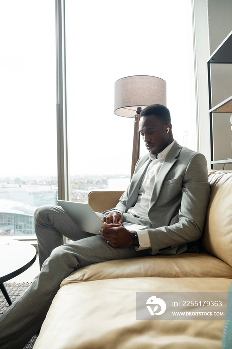 Young businessman sitting on sofa and using laptop