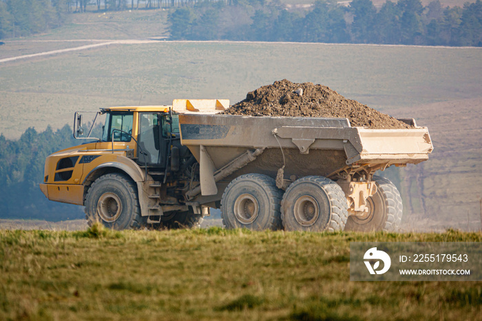 yellow Volvo A40E articulated dump truck earth mover fully laden with 25 tonne load driving across open countryside Wiltshire UK