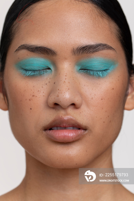 Portrait of brunette woman with blue makeup on closed eyes