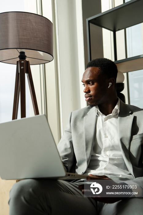 Young businessman sitting on sofa and using laptop