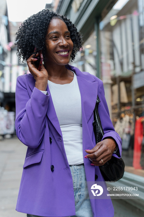 Smiling woman talking by smart phone in city