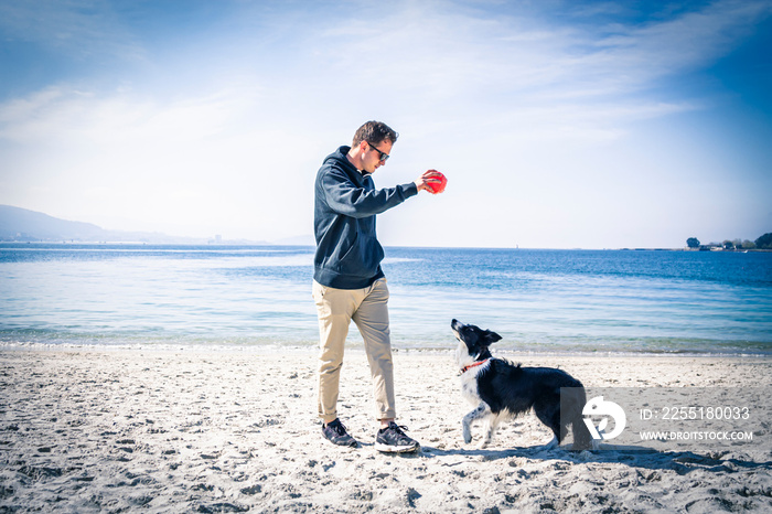 young man playing with his dog on the beach