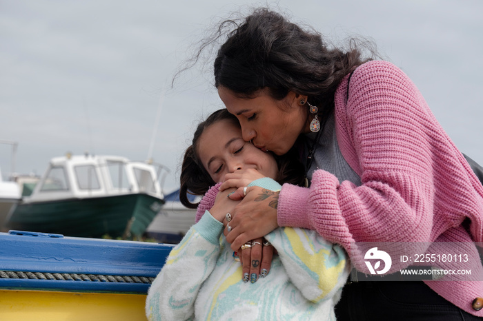 Portrait of mother kissing daughter in harbor