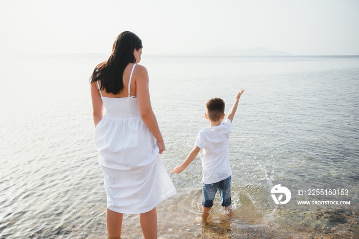 Happy mother and son walk along the ocean beach having great family time on vacation on Pandawa Beach, Bali. Paradise, travel, vacation concept