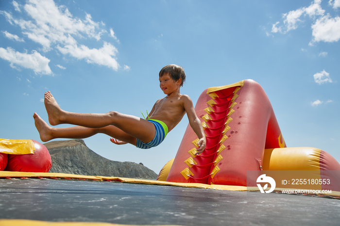 Boy playing on water trampoline on the sea at sunny day