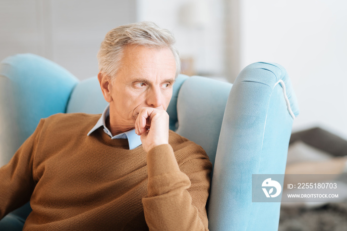 If I had my time over again. Thoughtful old gentleman sitting in a chair and musing over his memories while spending his day at home.