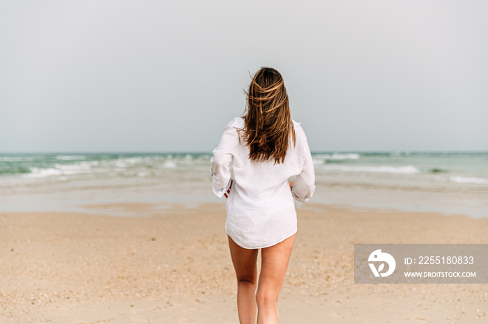 woman in white dress standing on sandy beach