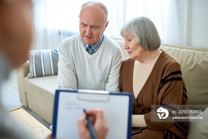 Portrait of nice senior couple visiting psychologist holding clipboard  sharing problems in therapy session