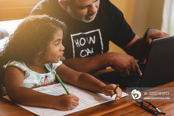 Padre e hija latinos compartiendo tiempo en casa mientras utilizan tecnología