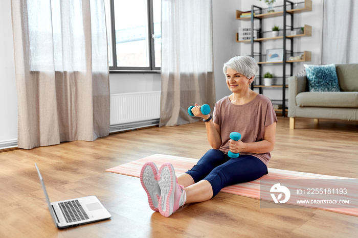 sport, fitness and healthy lifestyle concept - smiling senior woman with laptop computer and dumbbells exercising on mat at home