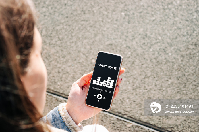 Audio tour guide online app on digital mobile smartphone. Happy young student woman holding phone listening audioguide. Digital library with audiobooks, podcasts, and courses.