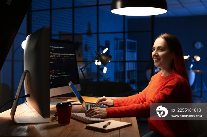 Female programmer working with computer in office at night