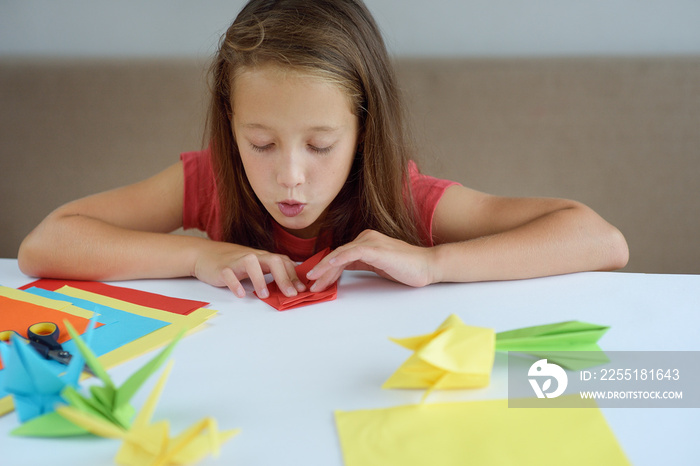 The girl puts origami from paper. lesson of origami