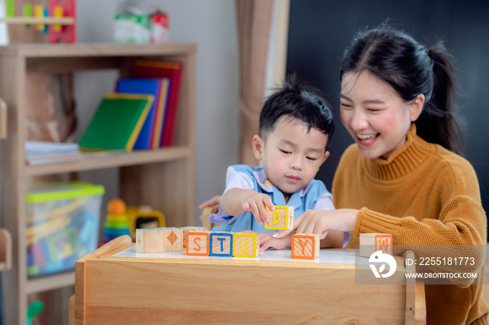 Asian student in preschool use a letter box make a study word in class room with his teacher