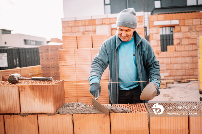 industrial details - Construction bricklayer worker building house walls with bricks, mortar and rubber hammer