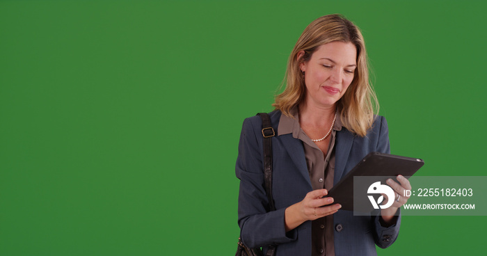 Middle aged adult businesswoman using tablet device on green screen